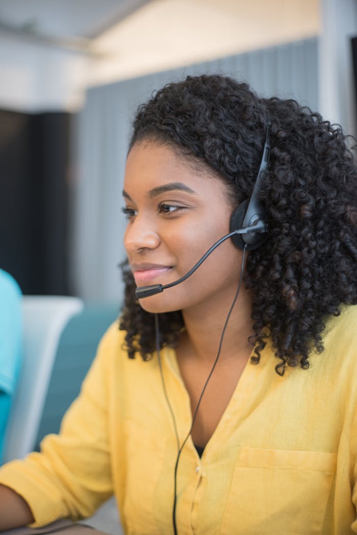 gallery-01 Focused call center agent with curly hair in a yellow blouse providing customer support.