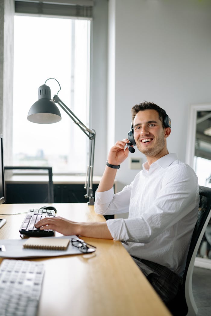 services-img A cheerful call center agent wearing headphones works at a modern office desk.